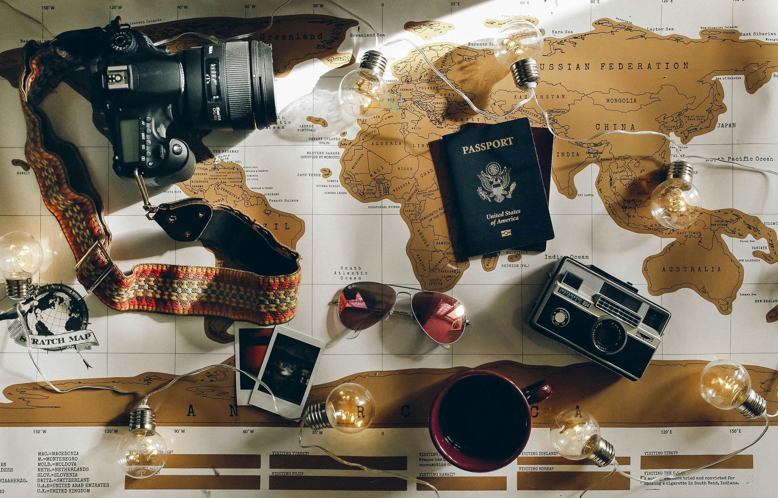 A passport, cameras and a scratch map laid out for planning a trip